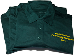 Folded up, green collard shirts with yellow embroidered lettering